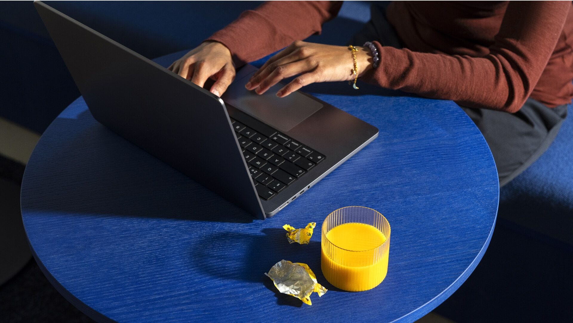 A person at Metacore's stylish offices sitting at a desk with a laptop, drinking juice and having candy.