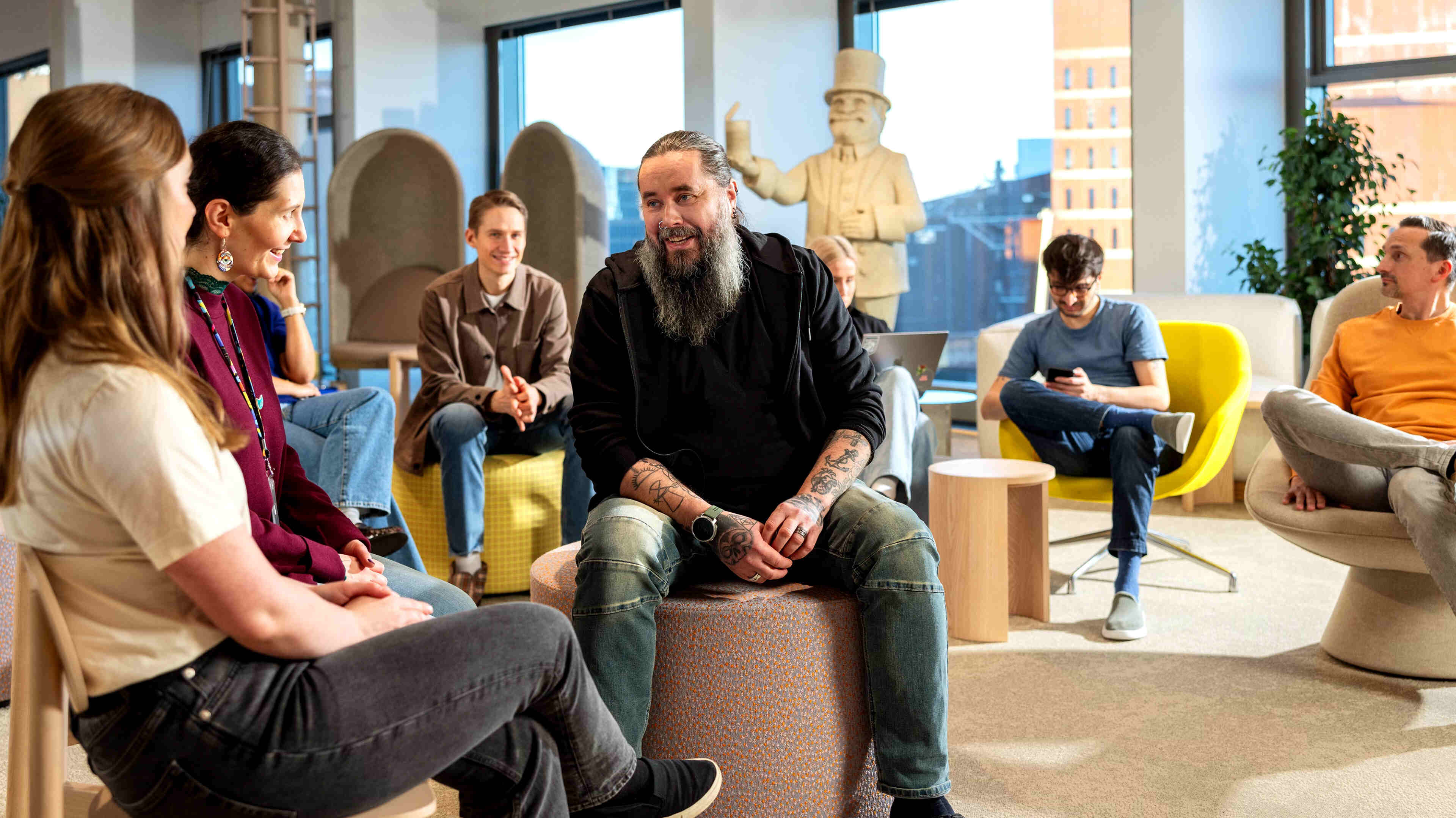 Metacore employees sitting in an open meeting room, discussing culture.