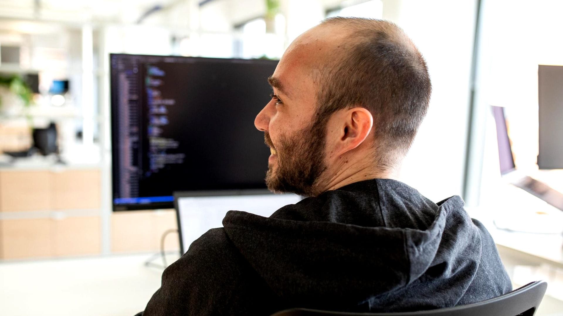 A person working at their desk at Metacore while smiling